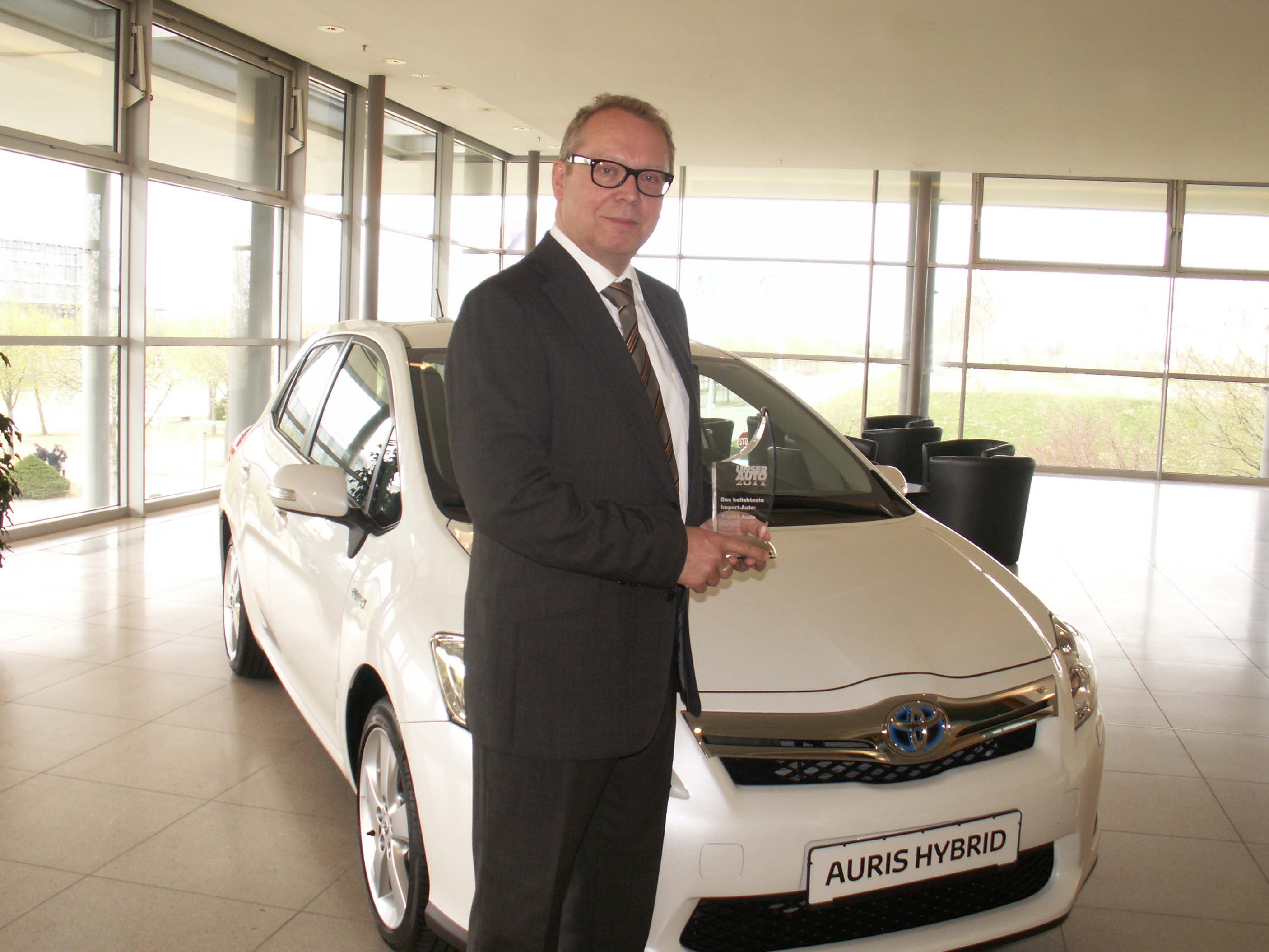 Jürgen Stolze, General Manager Öffentlichkeitsarbeit und Presse, übernimmt den Preis "Unser Auto 2011" für den Auris Hybrid