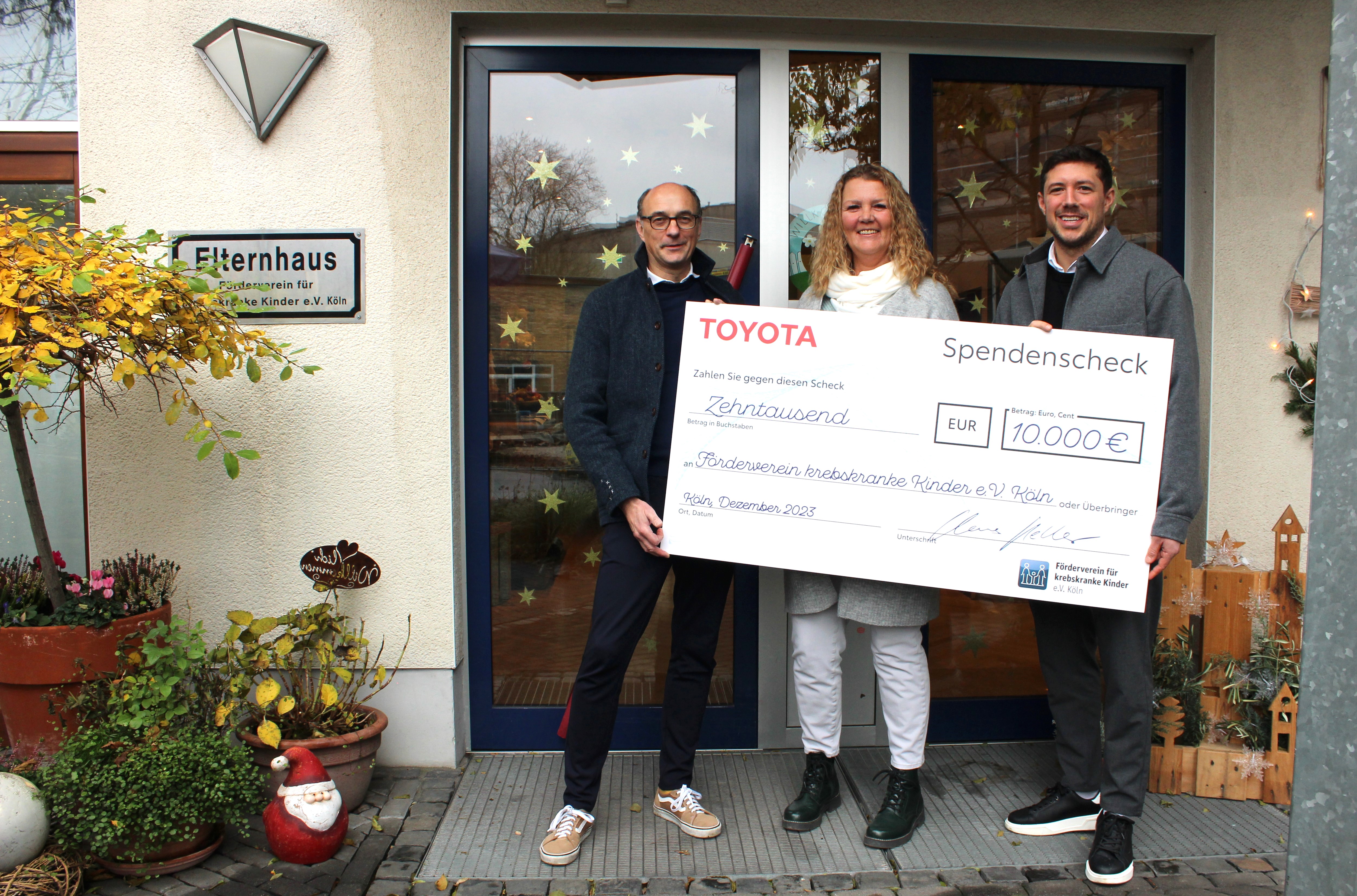 Claus Keller, General Manager People & Innovation Toyota Deutschland (li) und Andreas Landerl, Specialist Employer Branding Toyota Deutschland (re) übergeben den Scheck an Monika Burger-Schmidt, Geschäftsführerin Förderverein für krebskranke Kinder