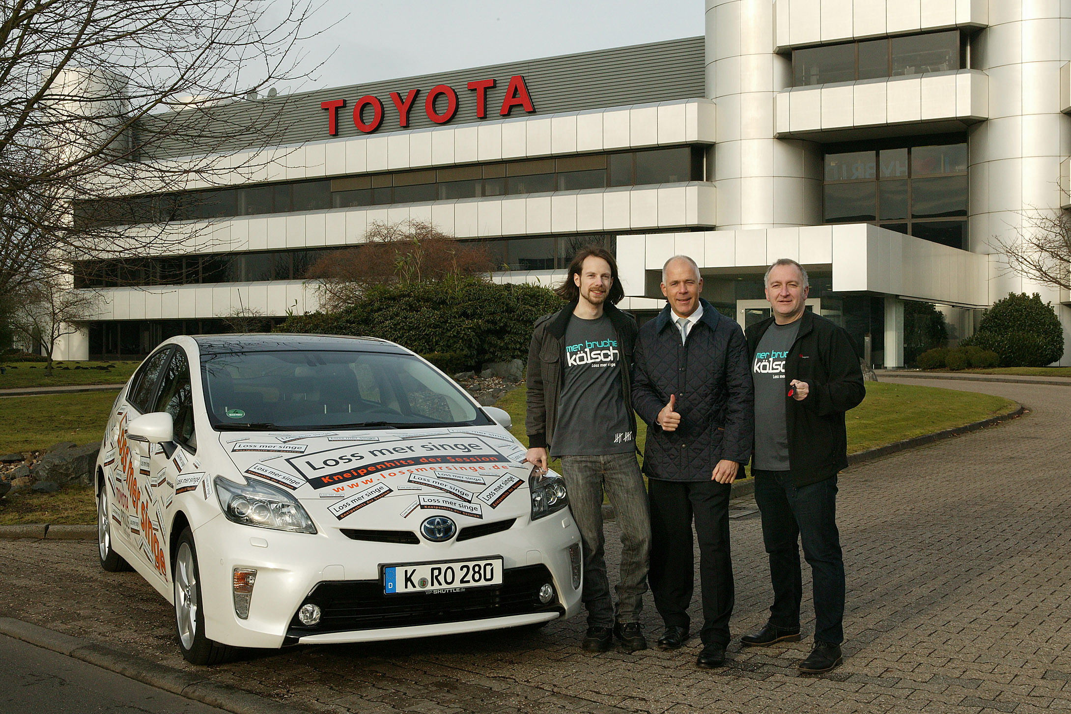 Ekkardt Sensendorf (Mitte), Abteilungsleiter Unternehmenskommunikation bei Toyota übergibt einen Toyota Prius an die Organisatoren von Loss mer singe. Rechts im Bild Georg Hinz, Gründer der Initiative.